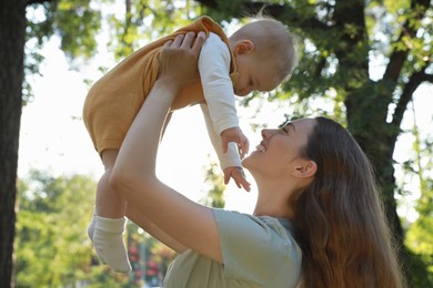 Beautiful mother with her cute daughter spending time together in park on summer day