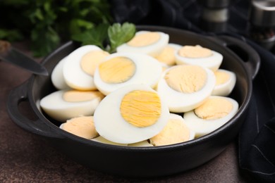 Fresh hard boiled eggs and parsley on brown table, closeup