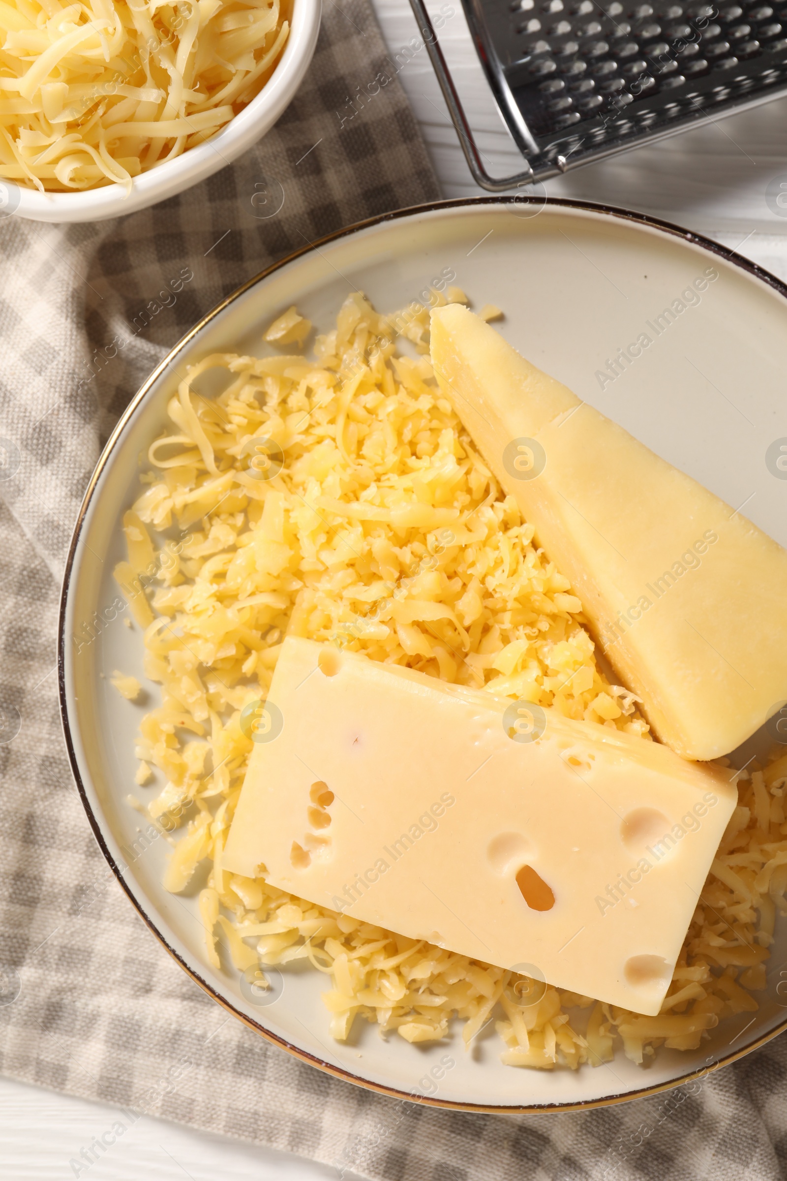 Photo of Grated and whole pieces of cheese on table, flat lay