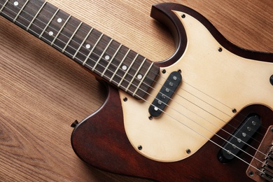 Modern electric guitar on wooden background, top view. Musical instrument