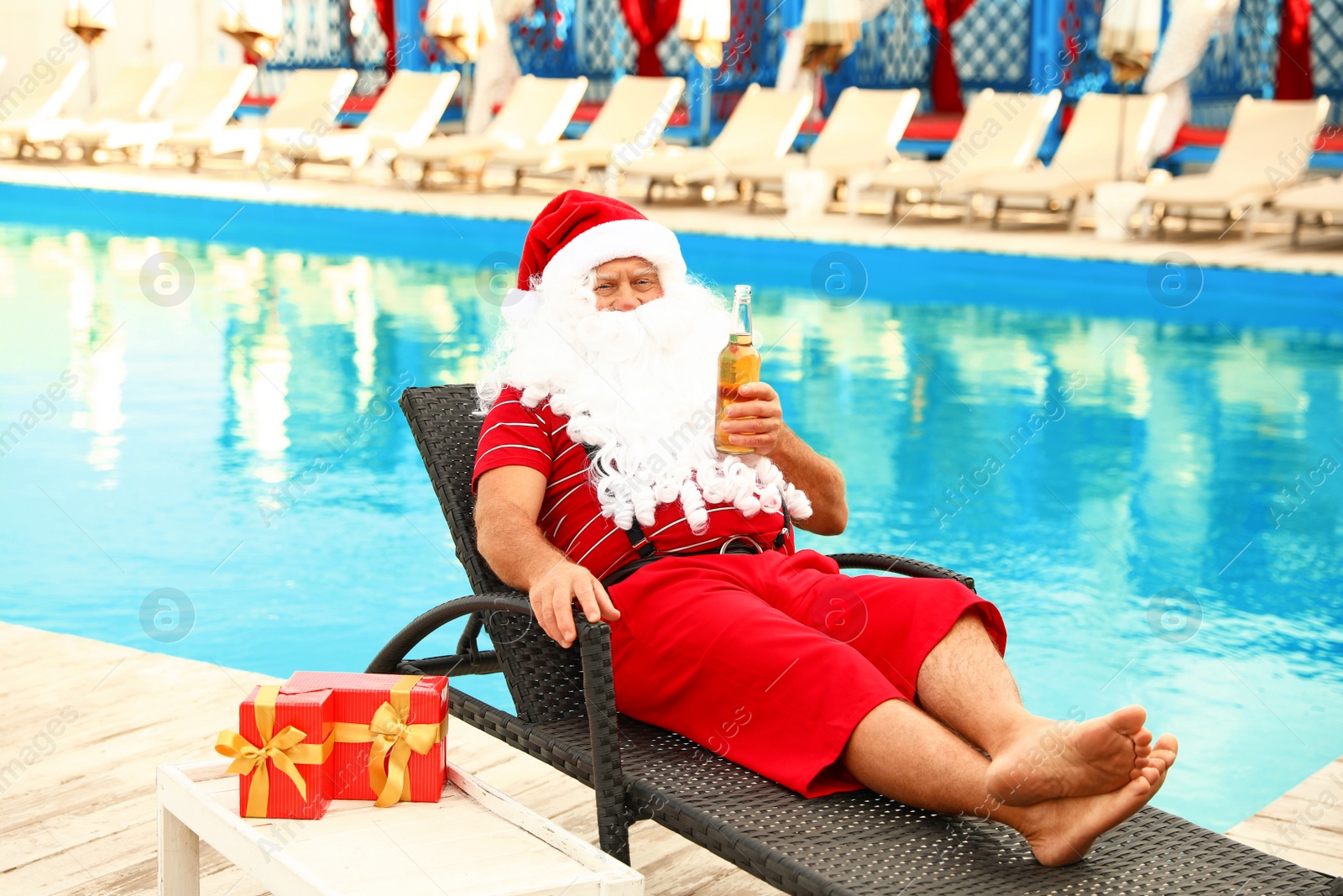 Photo of Authentic Santa Claus with bottle of beer near pool at resort