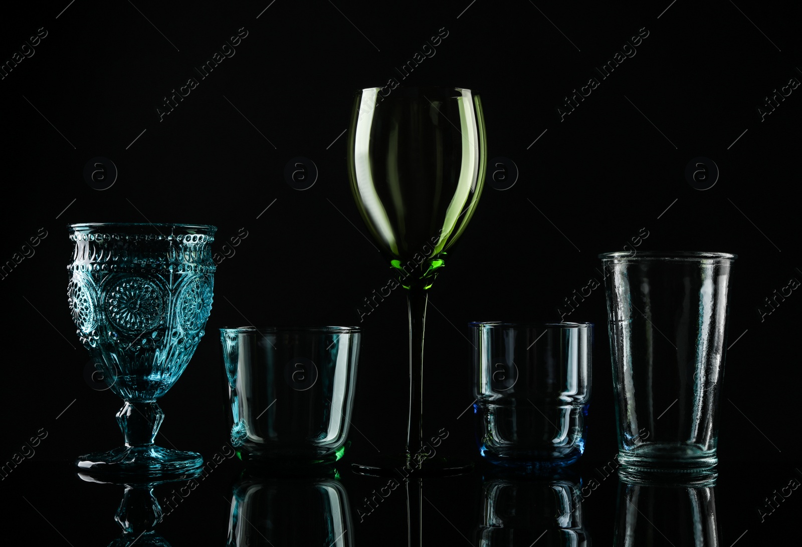 Photo of Set of different colorful empty glasses on black background