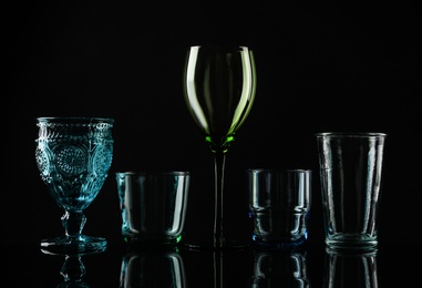 Photo of Set of different colorful empty glasses on black background