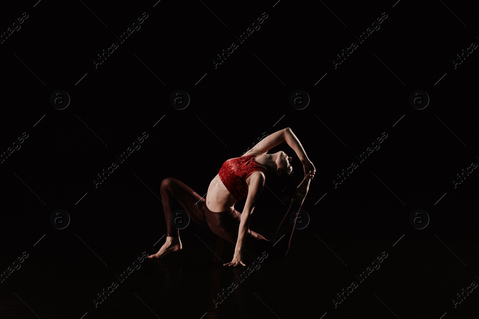 Photo of Young woman performing acrobatic element on stage indoors