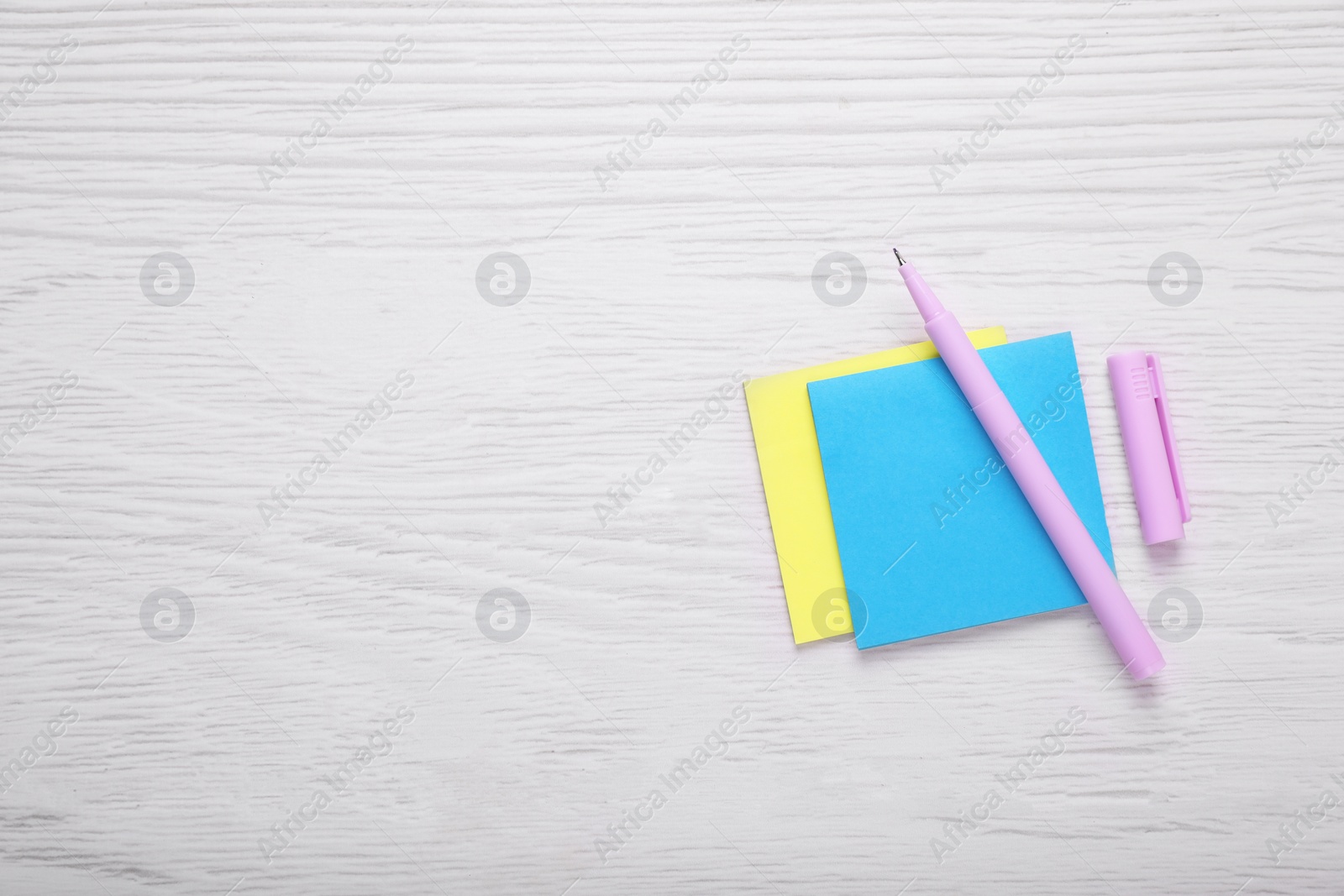 Photo of Paper notes and purple marker on white wooden background, flat lay. Space for text