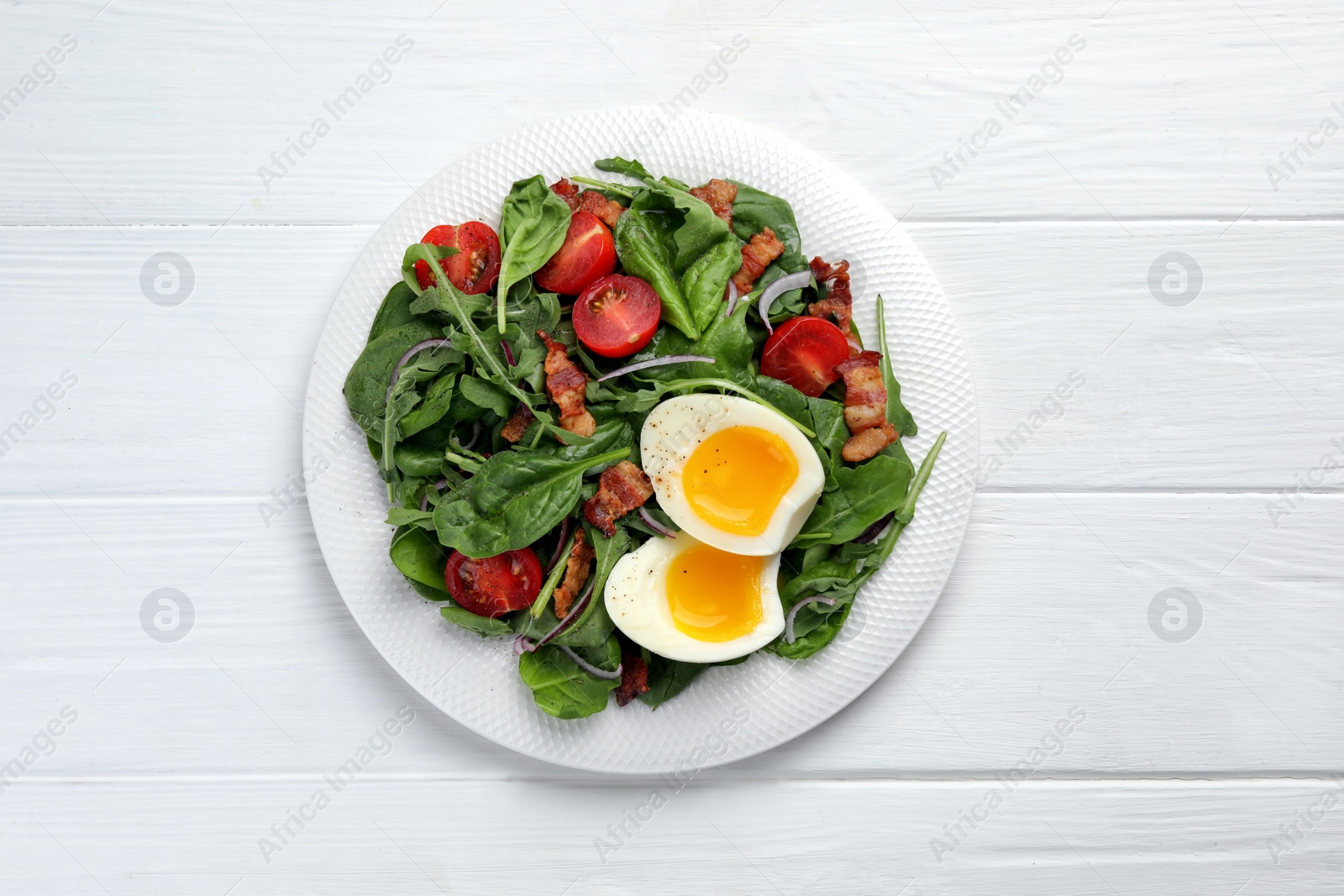 Photo of Delicious salad with boiled egg, bacon and tomatoes on white wooden table, top view
