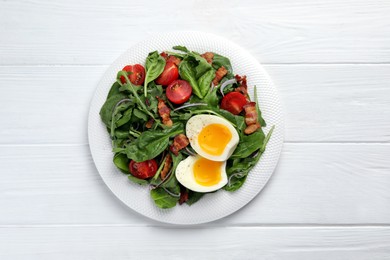 Delicious salad with boiled egg, bacon and tomatoes on white wooden table, top view