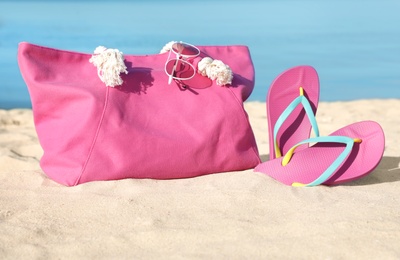 Photo of Stylish beach accessories on sand near sea