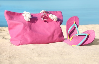 Stylish beach accessories on sand near sea