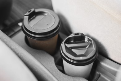 Coffee to go. Paper cups with tasty drink in holder inside of car, closeup