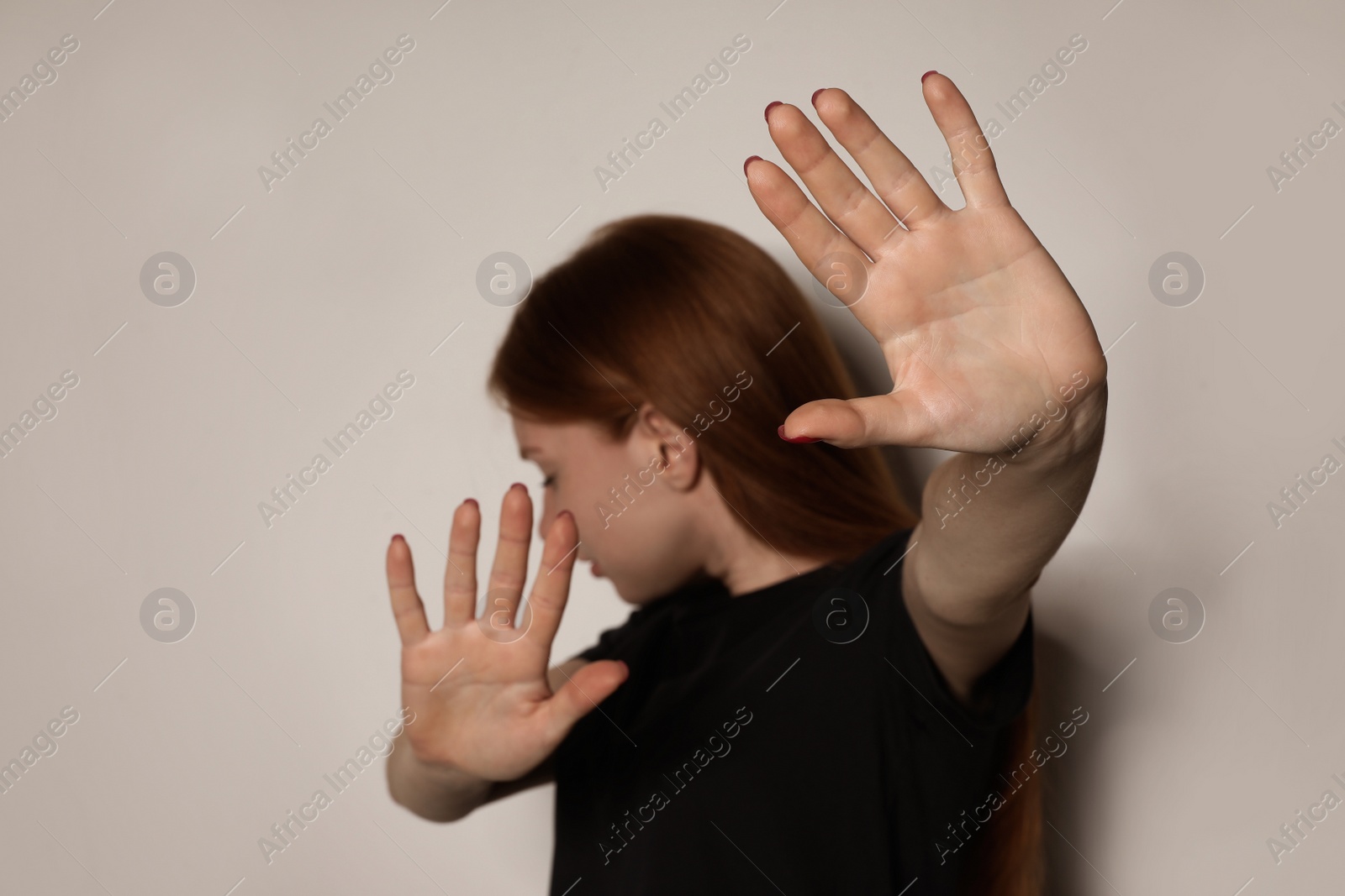 Photo of Young woman making stop gesture against light background, focus on hand