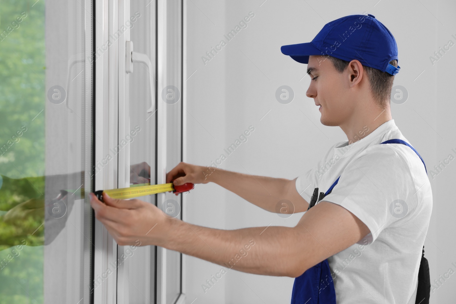 Photo of Worker measuring plastic window indoors. Installation process