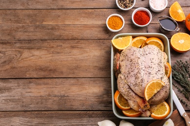 Raw chicken, orange slices and other ingredients on wooden table, flat lay. Space for text