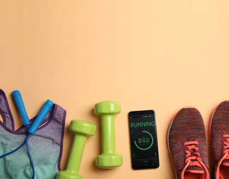 Photo of Flat lay composition with fitness equipment and smartphone on orange background. Space for text