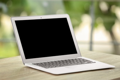 Photo of Modern laptop on table against window. Mock up with space for text