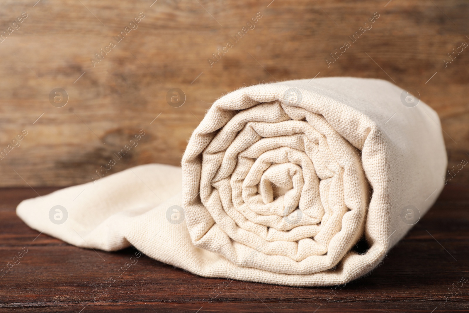 Photo of Beige hemp cloth on wooden table, closeup