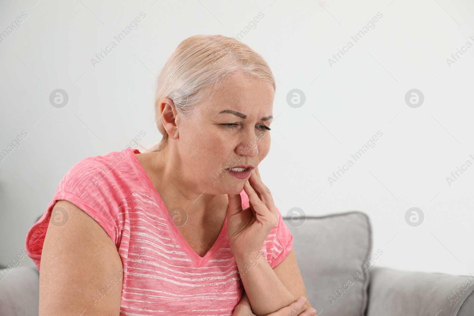 Photo of Mature woman suffering from strong tooth pain at home, space for text