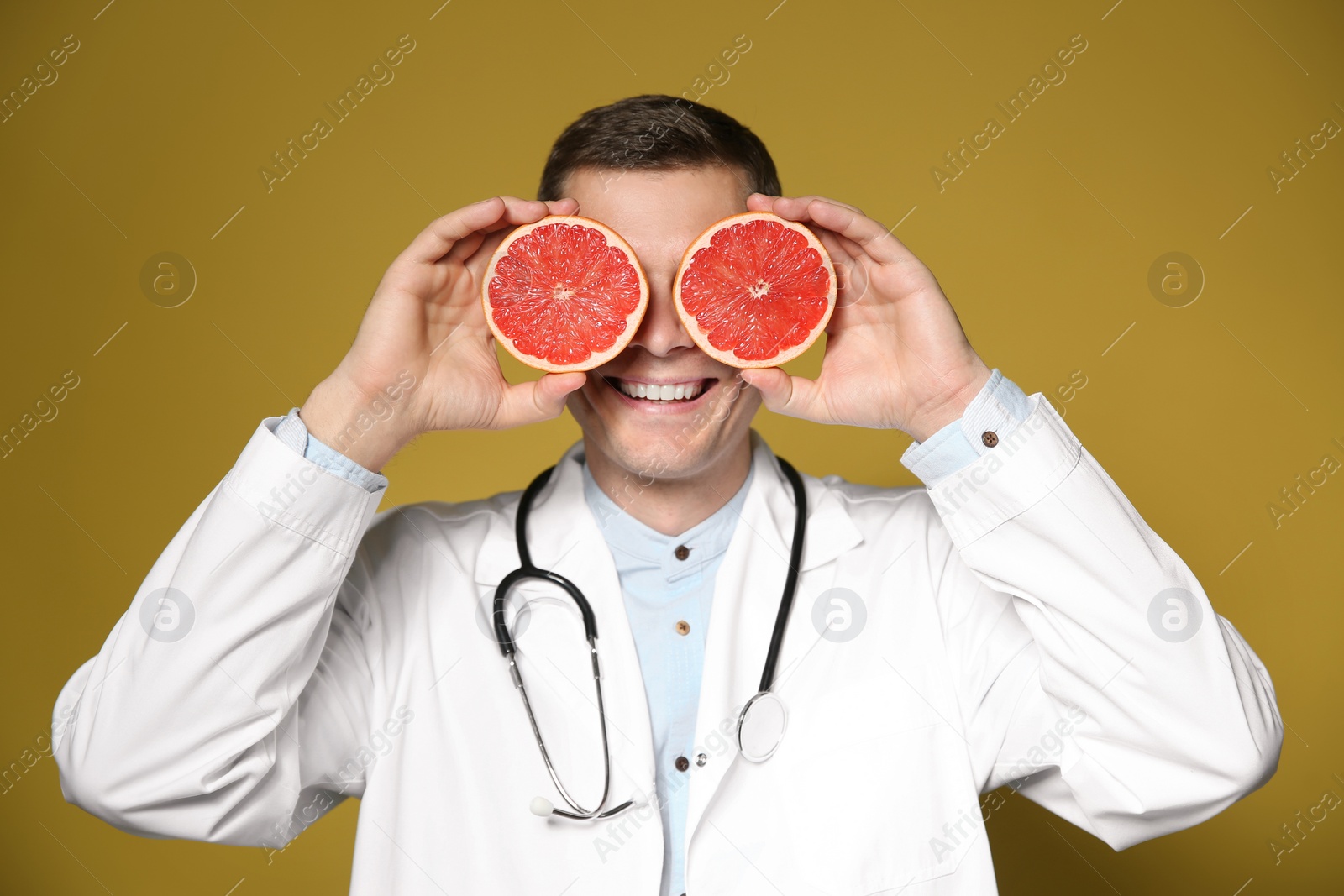Photo of Nutritionist posing with halves of ripe grapefruit on yellow background