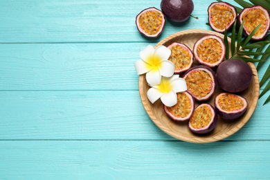 Photo of Passion fruits (maracuyas), palm leaves and flowers on light blue wooden table, flat lay. Space for text