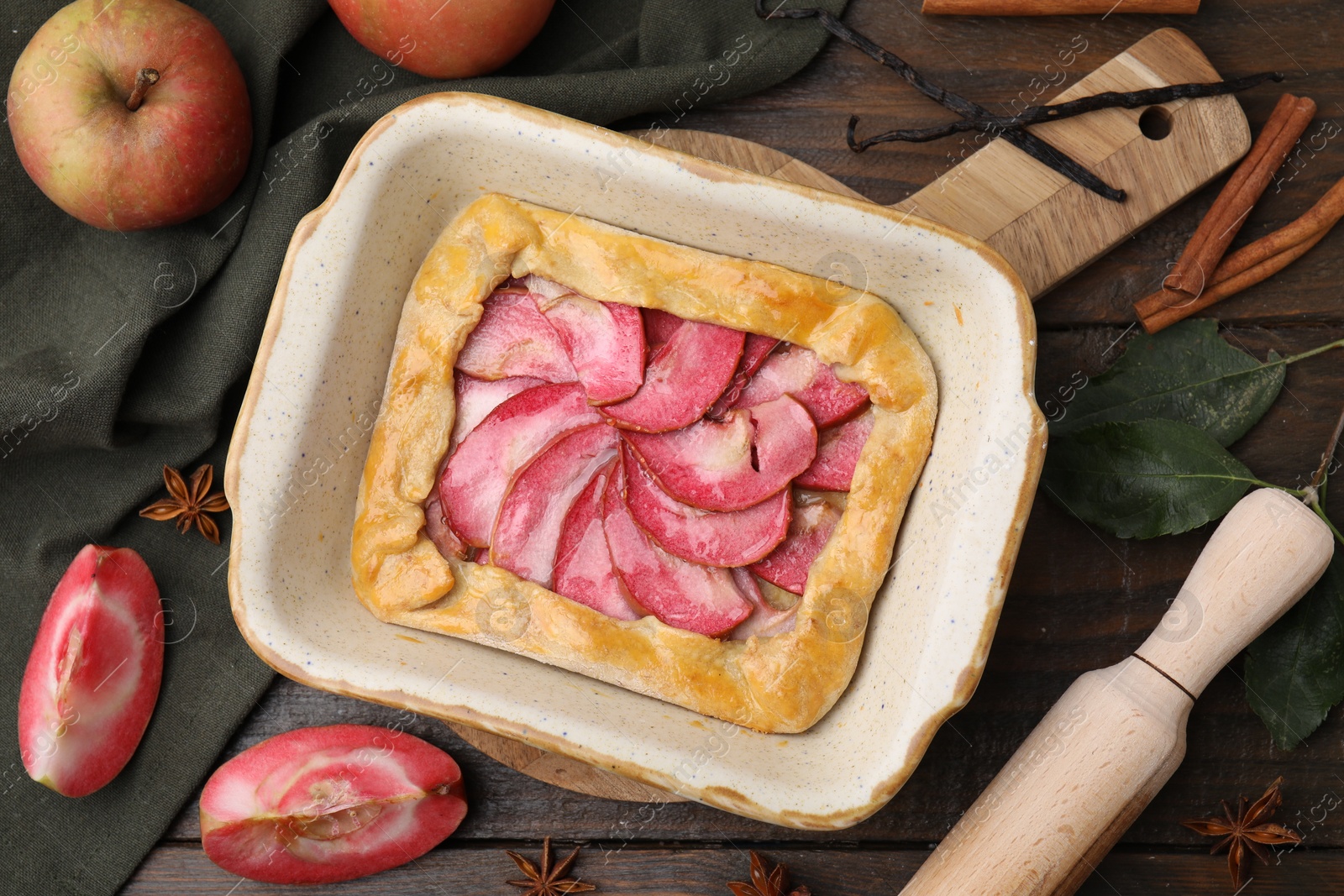 Photo of Delicious galette with apples, spices and fruit on wooden table, flat lay