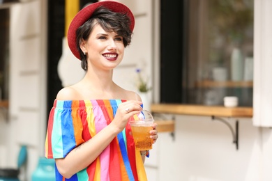 Young woman with cup of tasty lemonade outdoors