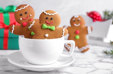 Photo of Gingerbread people in cup on white marble table, closeup