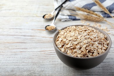 Photo of Bowl of oatmeal on white wooden table. Space for text