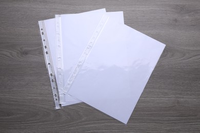 Punched pockets with paper sheets on wooden table, flat lay