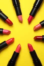 Photo of Frame of bright lipsticks on yellow background, flat lay. Space for text