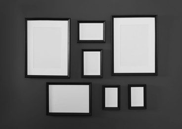 Photo of Empty frames on black wall. Mockup for design