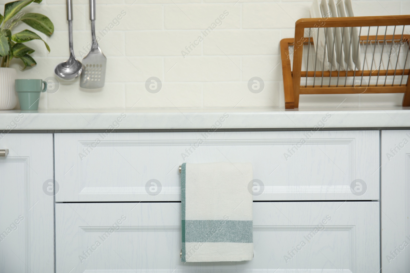 Photo of Clean towel hanging on drawer handle in kitchen