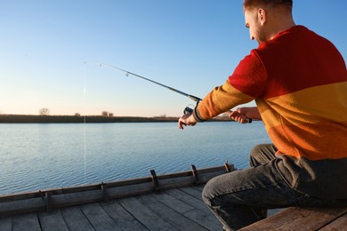 Photo of Fisherman with fishing rod at riverside on sunny day