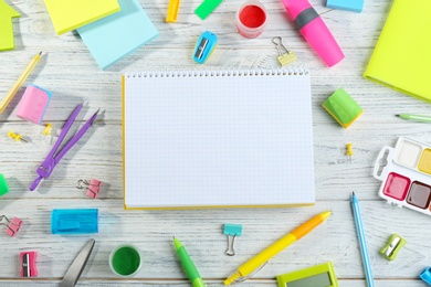 Photo of Different school stationery and blank notebook on white wooden background, flat lay. Space for text