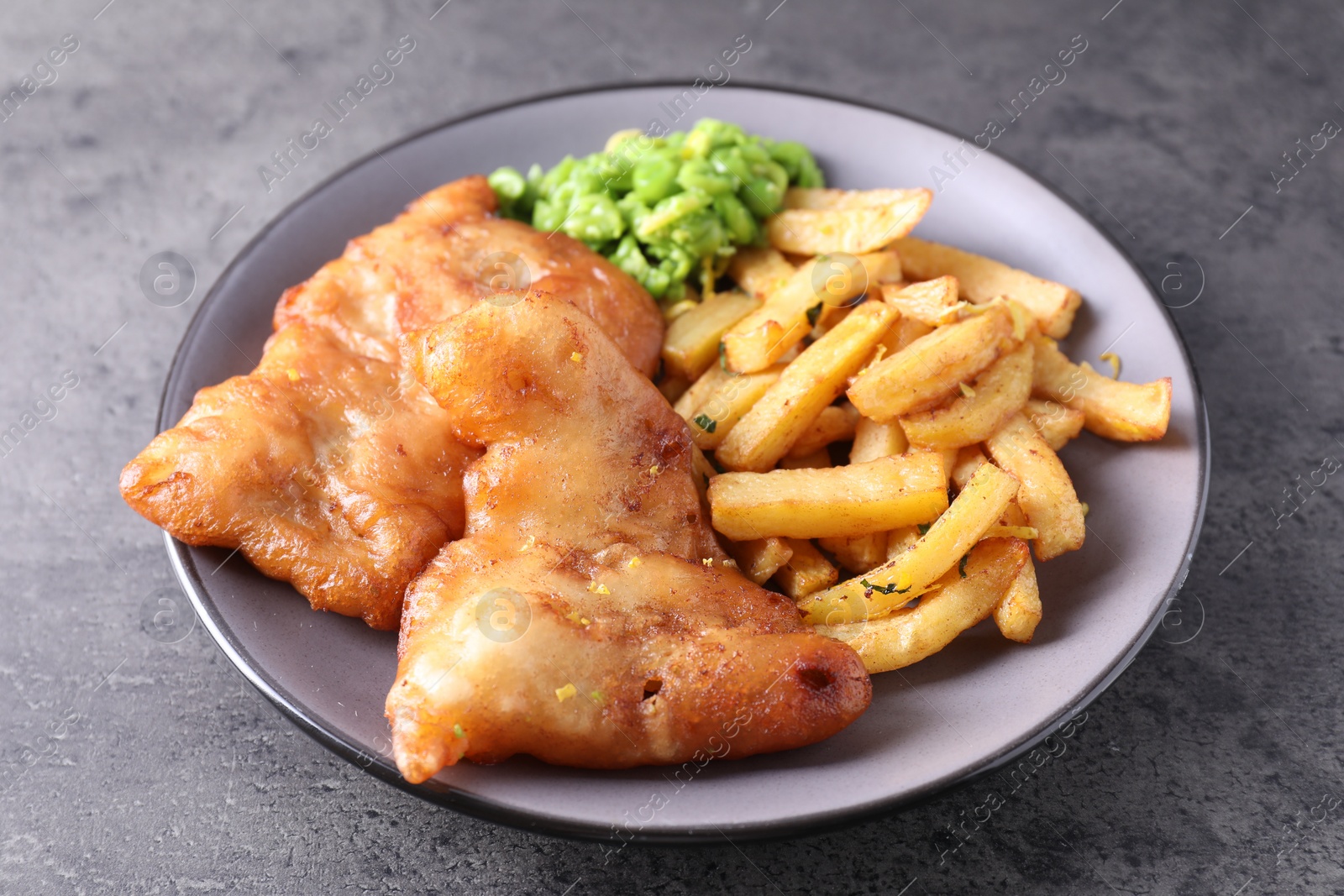 Photo of Tasty fish, chips and peas on grey table