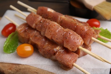 Photo of Skewers with cut raw marinated meat on wooden table, closeup
