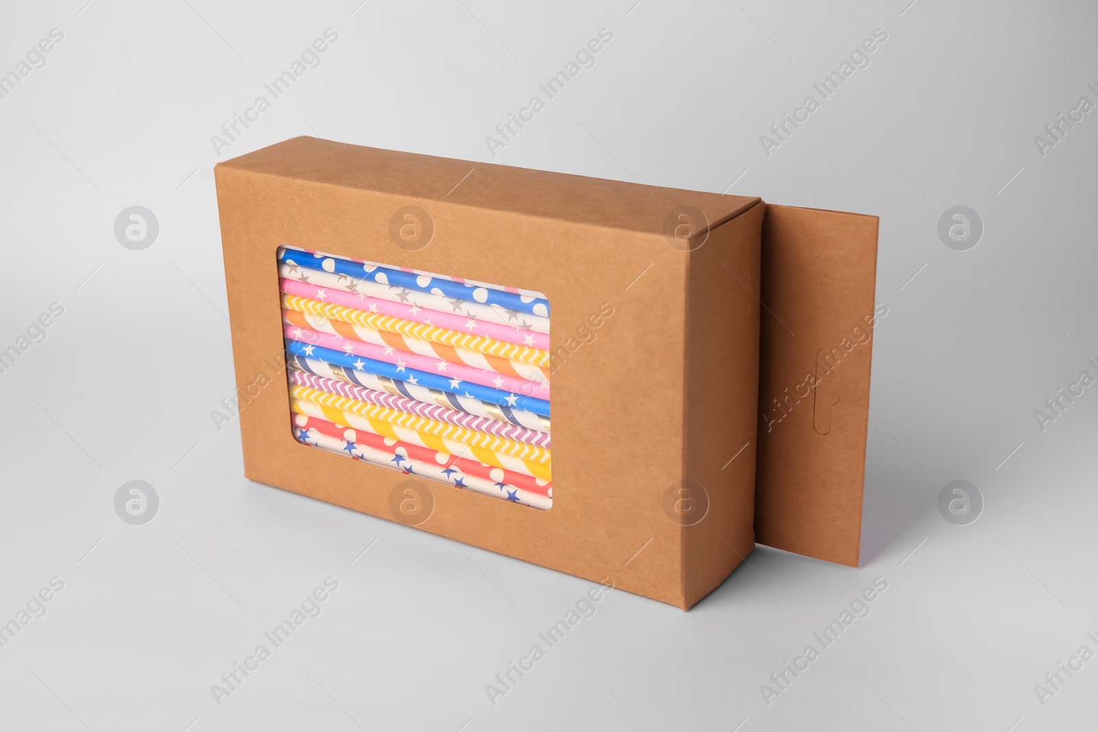 Photo of Box with many paper drinking straws on light grey background