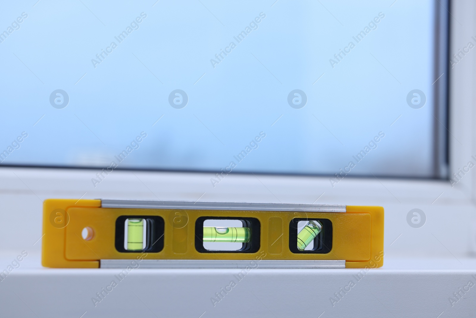 Photo of Yellow building level on white windowsill indoors, space for text