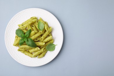 Photo of Delicious pasta with pesto sauce and basil on light grey background, top view. Space for text