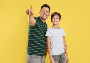 Portrait of dad and his son on color background