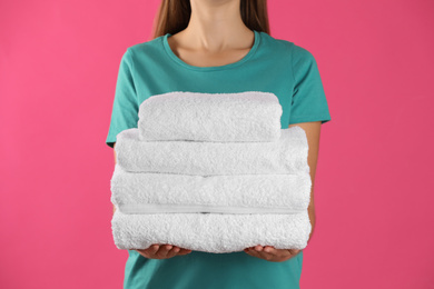 Photo of Woman holding fresh towels on pink background, closeup