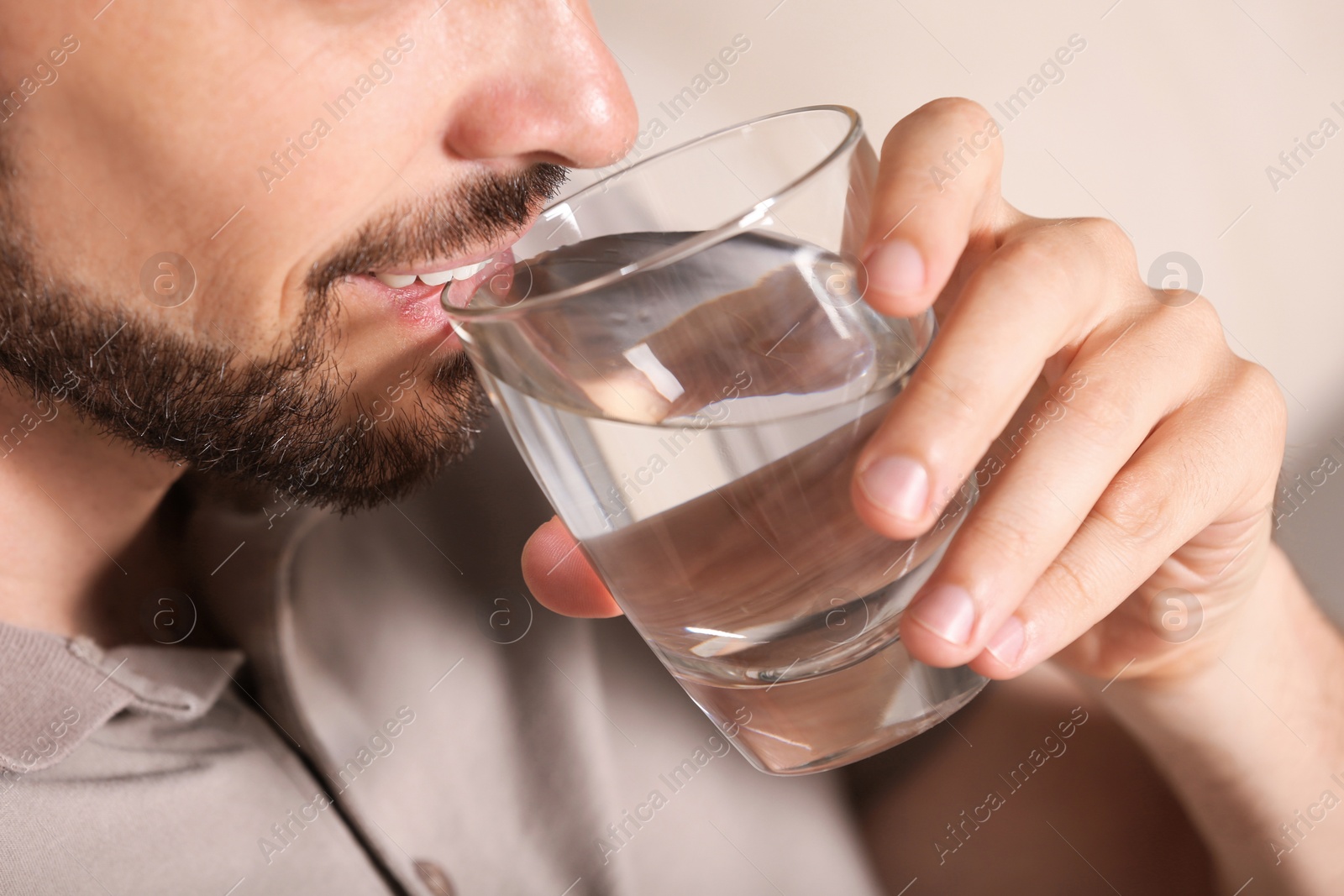 Photo of Man drinking water on blurred background, closeup. Refreshing drink