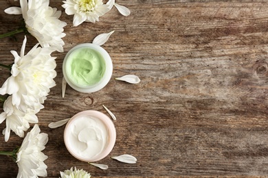 Beautiful composition with cream and flowers on wooden background, flat lay