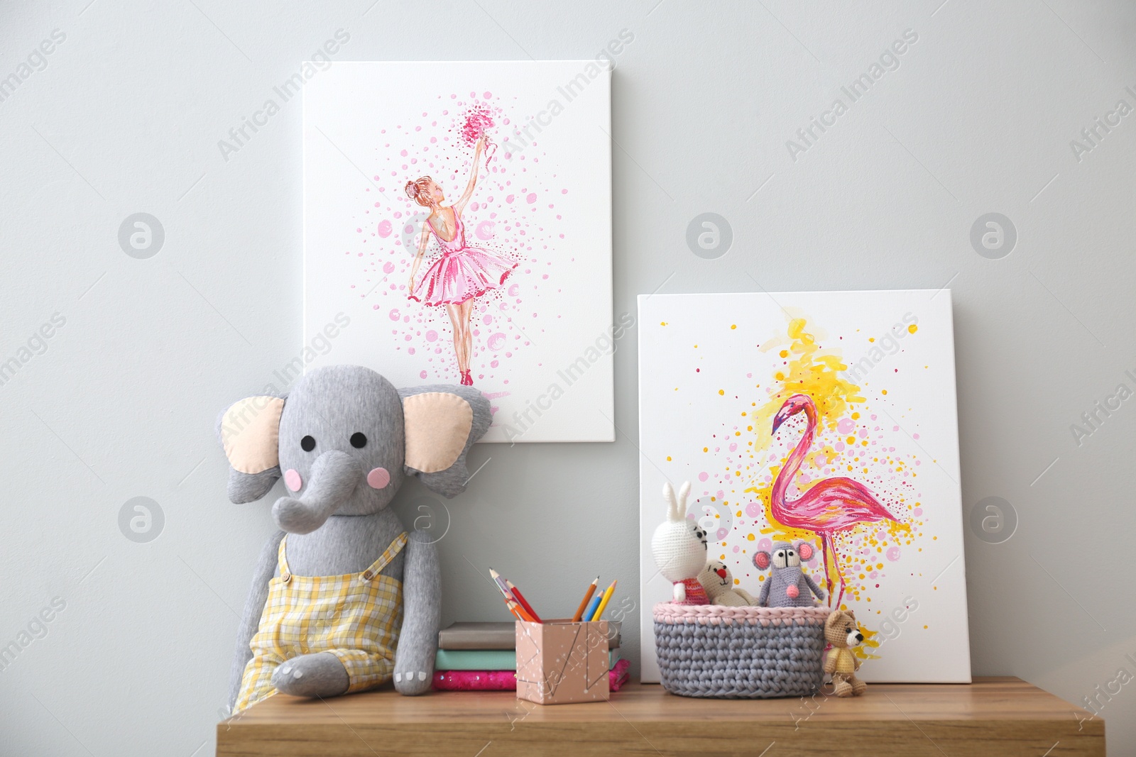 Photo of Pictures and stationery with toys on wooden table in children's room. Interior design