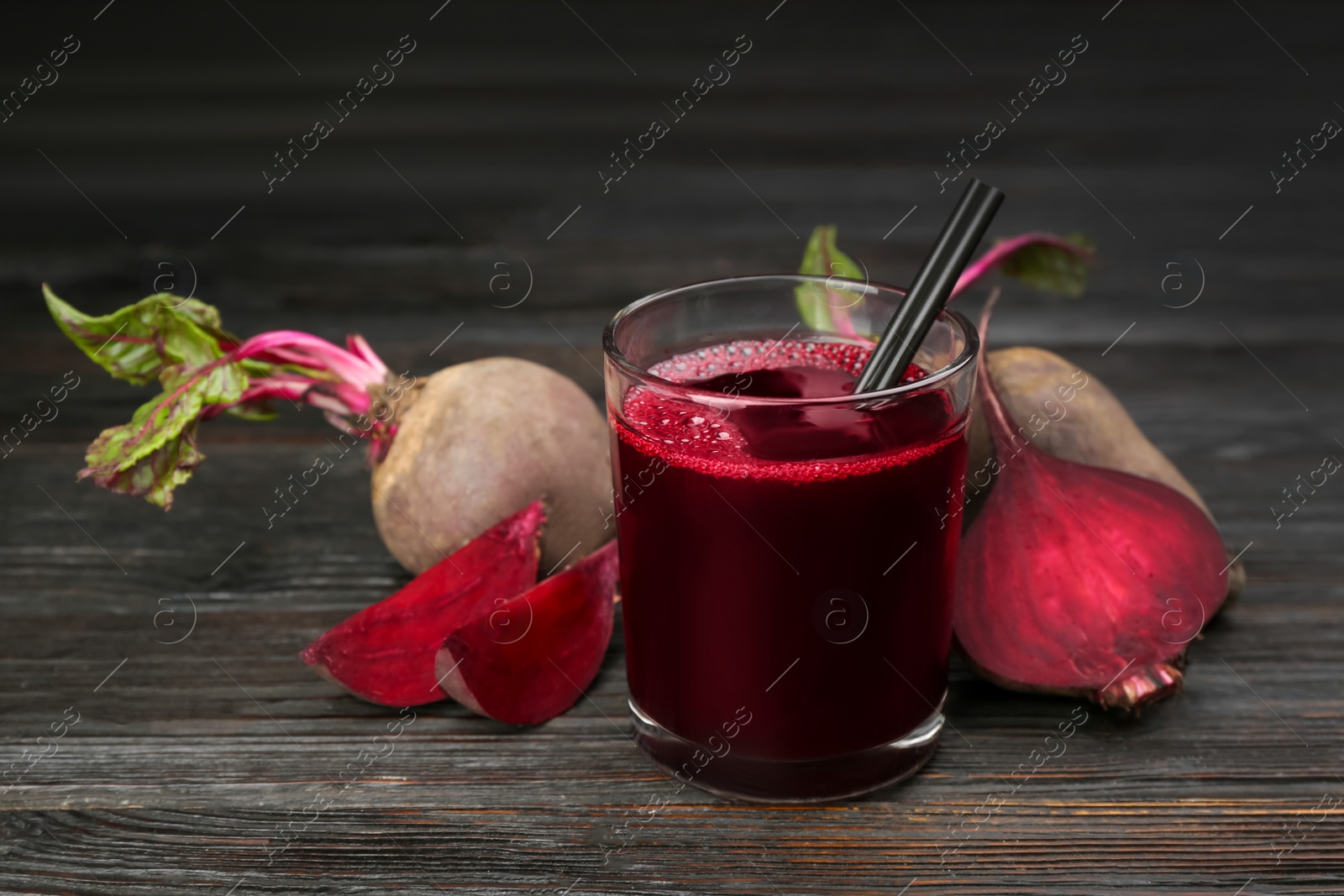 Photo of Fresh beet juice and raw vegetable on dark wooden table