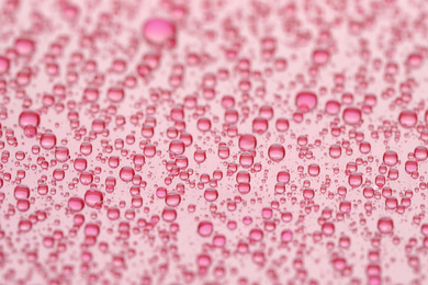 Photo of Water drops on pink background, closeup view