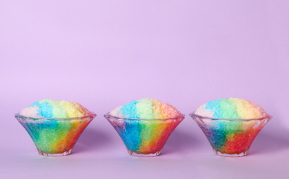 Photo of Rainbow shaving ice in glass dessert bowls on violet background