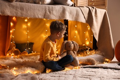 Boy playing with toy bunny in play tent at home