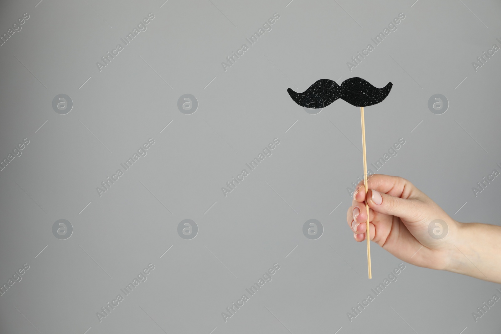 Photo of Woman with fake paper mustache on gray background, closeup. Space for text