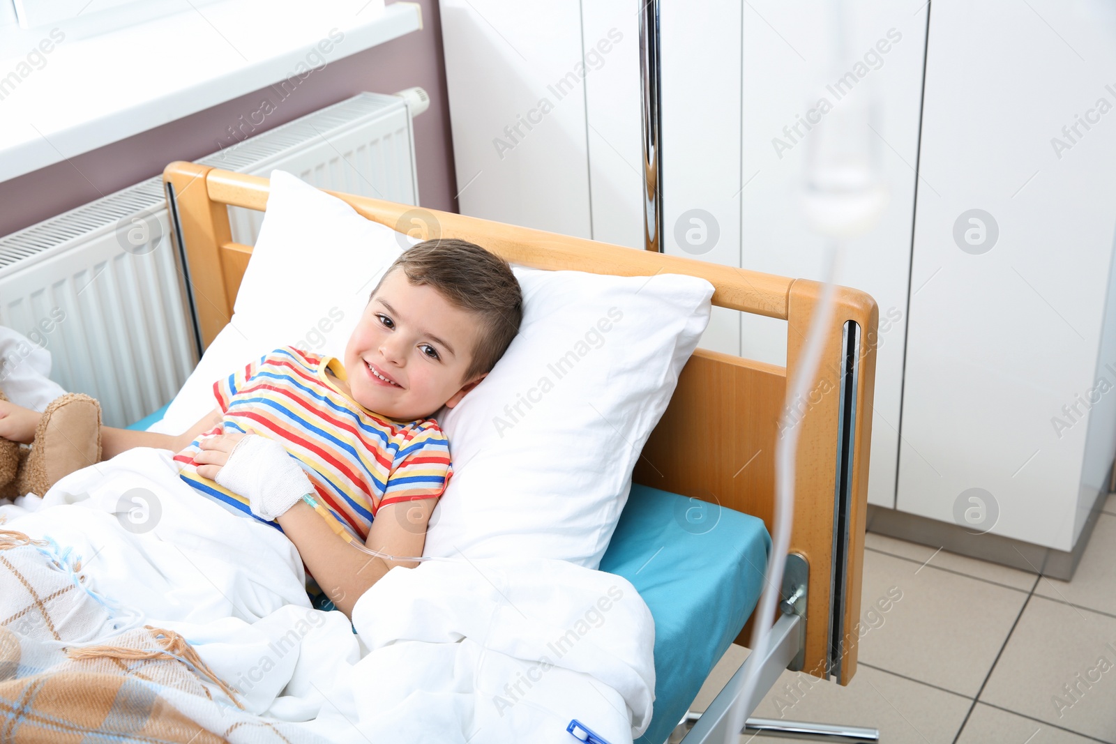 Photo of Little child with intravenous drip in hospital bed