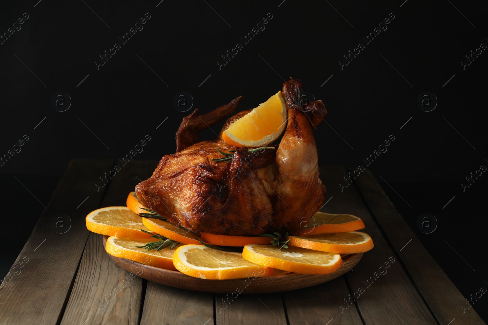 Photo of Baked chicken with orange slices on wooden table